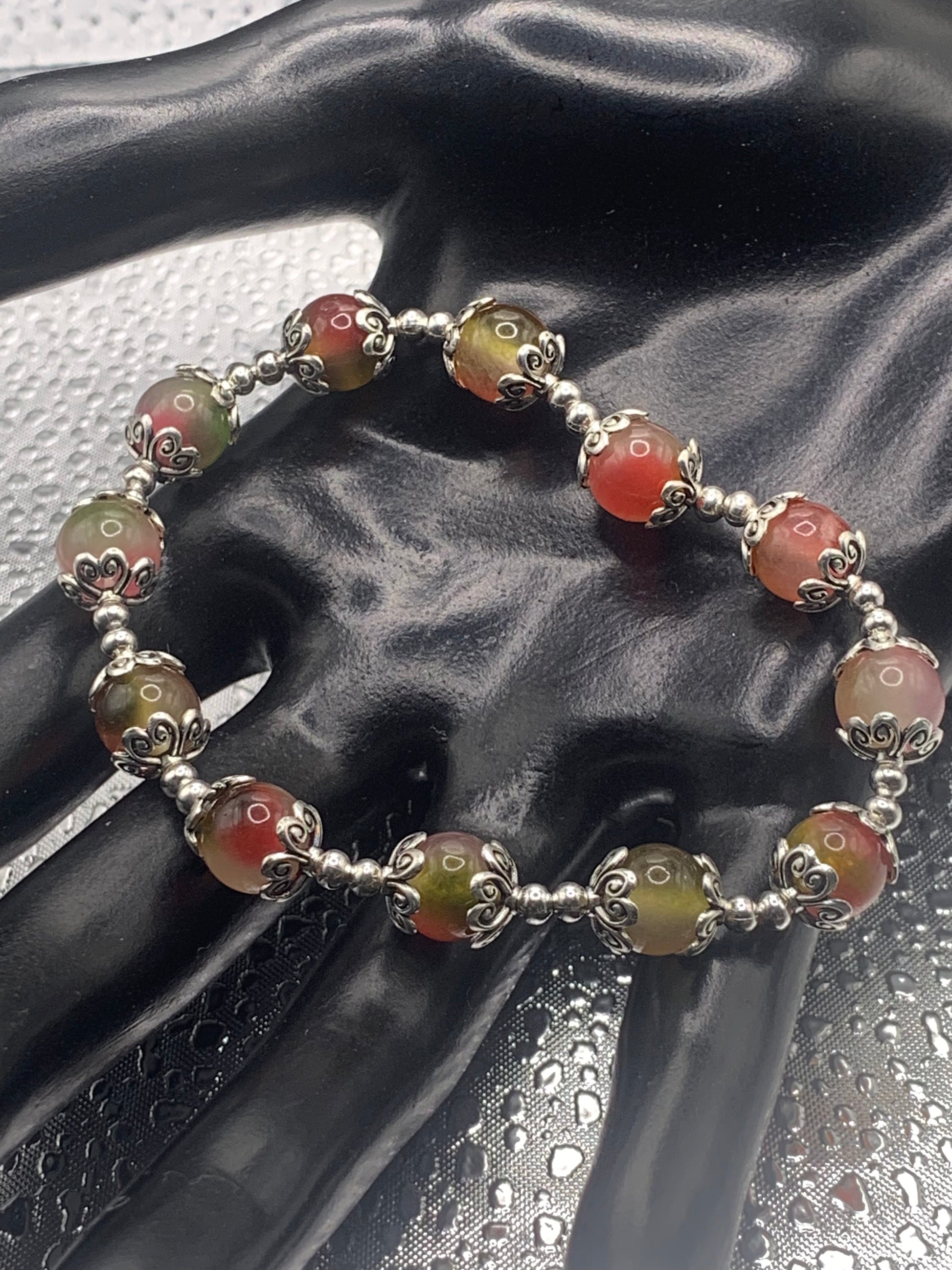 This bracelet contains watermelon agate beads that are surrounded by bead caps and spacer beads