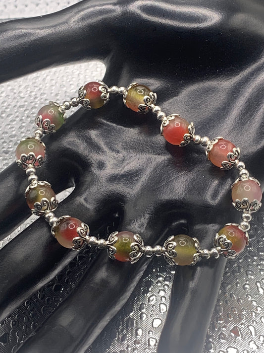 This bracelet contains watermelon agate beads that are surrounded by bead caps and spacer beads