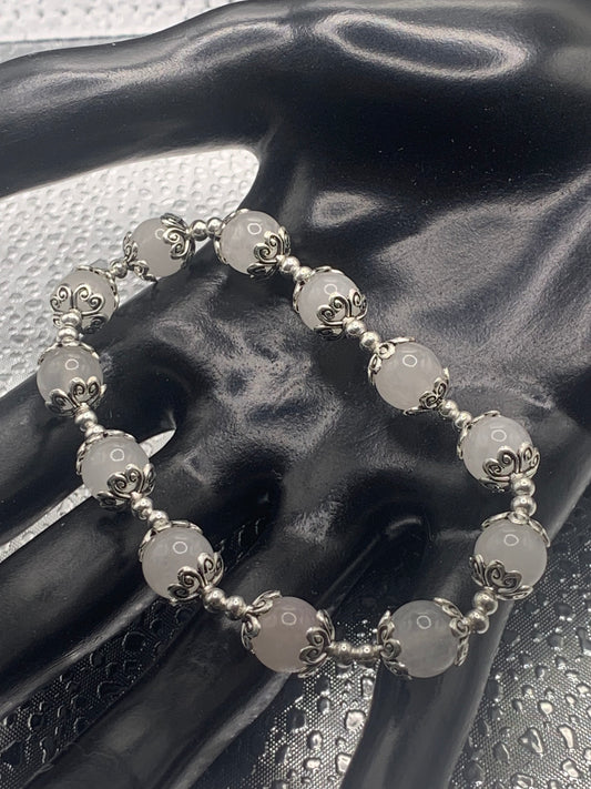 This bracelet contains white chalcedony beads that are surrounded by bead caps and spacer beads