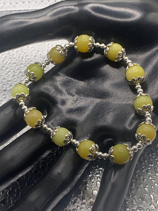 This bracelet contains yellow jade beads that are surrounded by bead caps and spacer beads